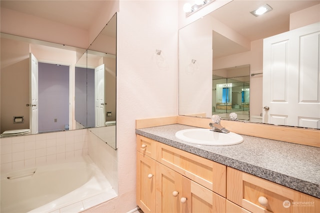 bathroom featuring a tub, vanity with extensive cabinet space, and toilet