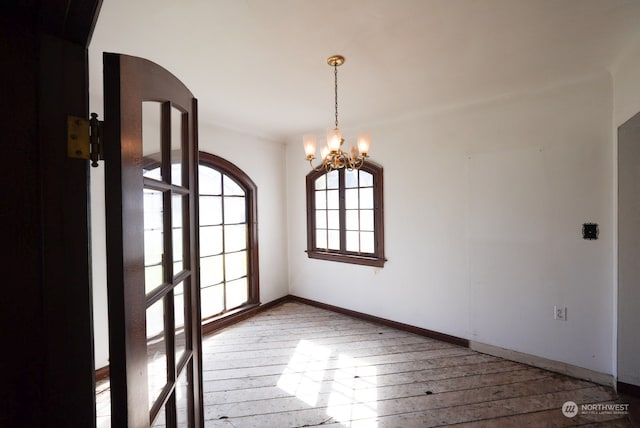 unfurnished room featuring wood-type flooring and a chandelier