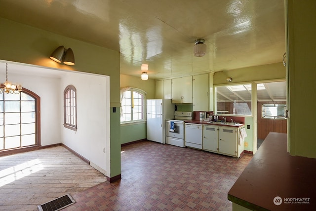 kitchen with a notable chandelier, white appliances, sink, and tile floors