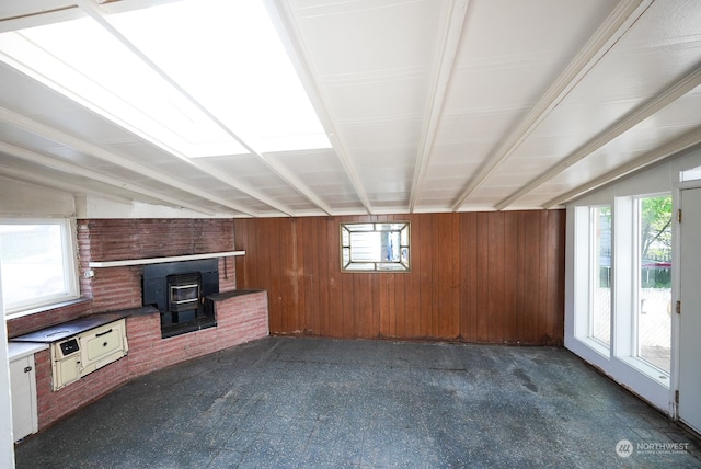 unfurnished living room with a wood stove and wood walls