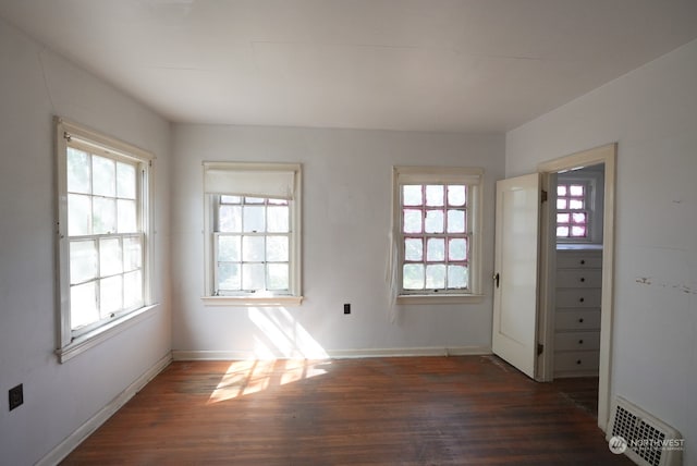 unfurnished room featuring a wealth of natural light and dark hardwood / wood-style flooring