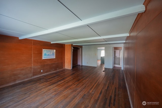 empty room featuring beamed ceiling and dark wood-type flooring