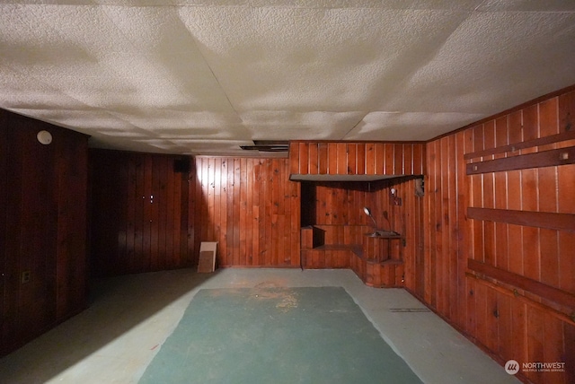 basement featuring wood walls and a textured ceiling