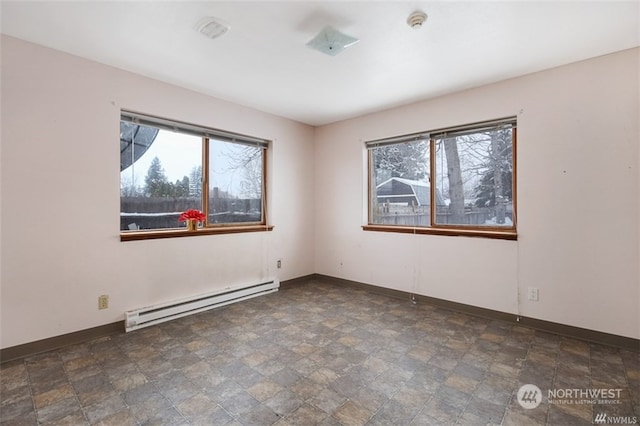 spare room with a wealth of natural light, a baseboard heating unit, and dark tile flooring