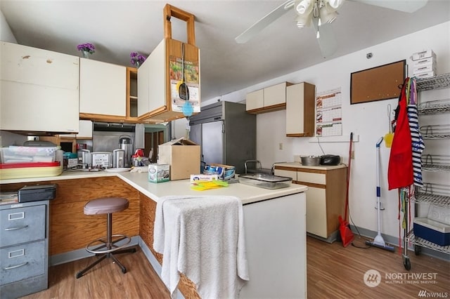 kitchen with kitchen peninsula, light hardwood / wood-style flooring, ceiling fan, and stainless steel fridge