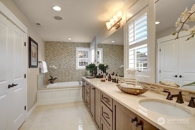 bathroom featuring backsplash, tile patterned floors, a tub to relax in, and vanity