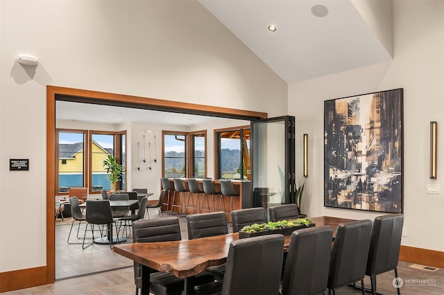 dining space featuring visible vents, high vaulted ceiling, and baseboards