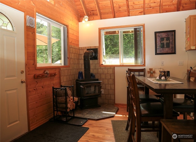 dining area featuring wooden ceiling, lofted ceiling with beams, a wood stove, and hardwood / wood-style flooring