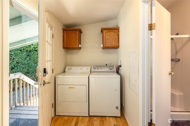 clothes washing area featuring cabinet space, light wood-style floors, and washing machine and clothes dryer