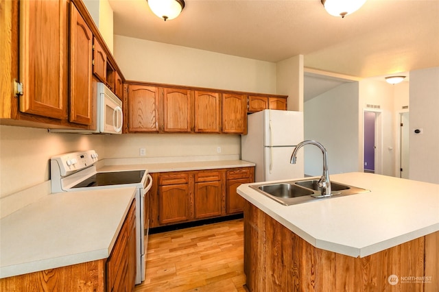 kitchen featuring white appliances, a sink, light countertops, light wood-style floors, and brown cabinets