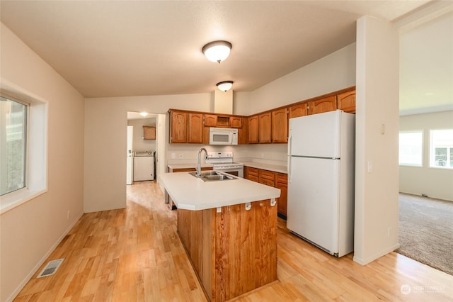 kitchen featuring visible vents, a kitchen island with sink, a sink, white appliances, and light countertops