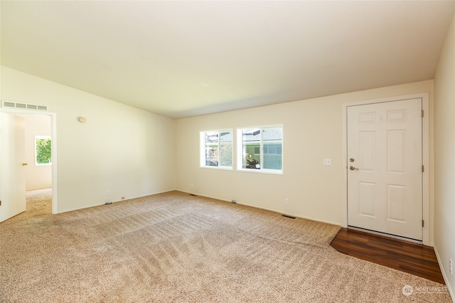 carpeted empty room featuring visible vents, plenty of natural light, and vaulted ceiling