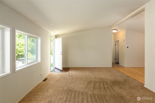 carpeted spare room featuring visible vents, lofted ceiling, and baseboards