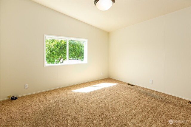 spare room featuring visible vents, baseboards, lofted ceiling, and carpet floors