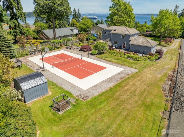 view of sport court with a water view, tennis court, and a lawn