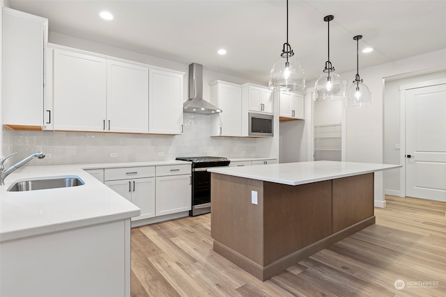 kitchen featuring a center island, white cabinets, wall chimney range hood, and stainless steel appliances