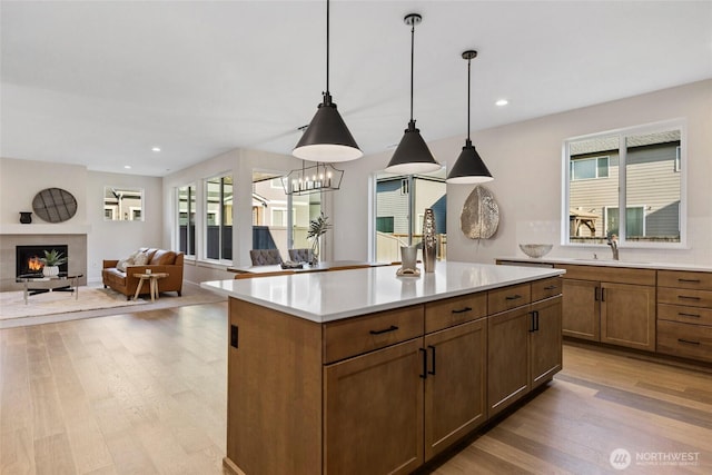 kitchen with light hardwood / wood-style flooring, sink, a premium fireplace, a center island, and hanging light fixtures