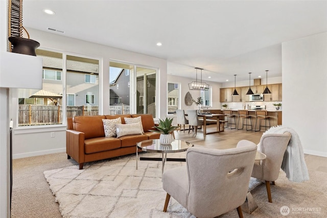 carpeted living room featuring a notable chandelier