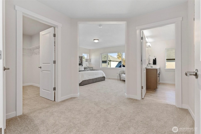 bedroom featuring sink, light colored carpet, and a walk in closet