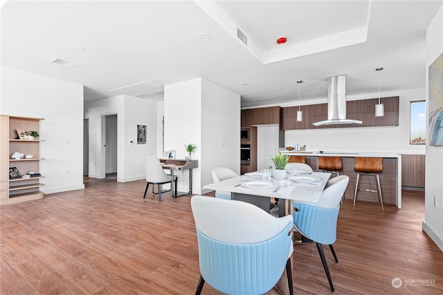 dining space featuring a tray ceiling and light hardwood / wood-style flooring