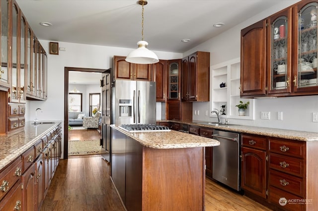 kitchen with appliances with stainless steel finishes, sink, hardwood / wood-style flooring, and a kitchen island