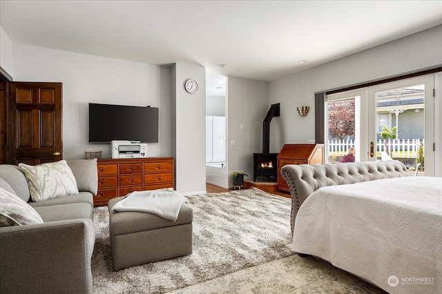 bedroom featuring access to outside, hardwood / wood-style floors, and a wood stove