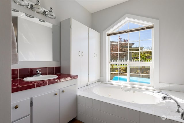 bathroom with tiled tub and vanity