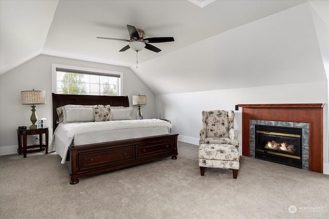 carpeted bedroom with ceiling fan, vaulted ceiling, and a high end fireplace