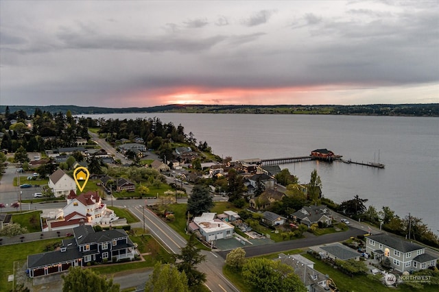 aerial view at dusk featuring a water view