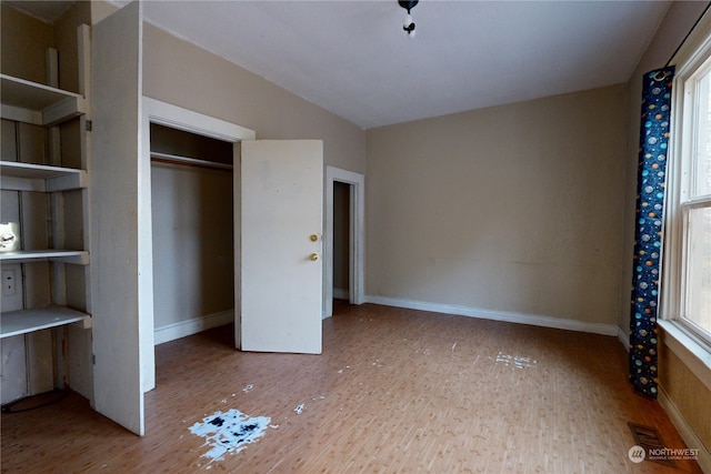 unfurnished bedroom with vaulted ceiling and light hardwood / wood-style floors