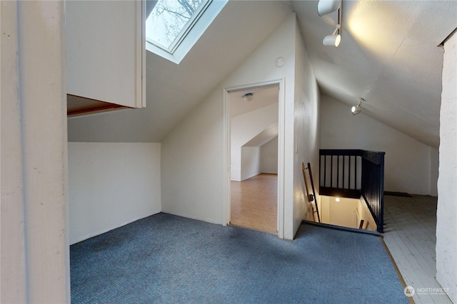 additional living space featuring vaulted ceiling with skylight and carpet