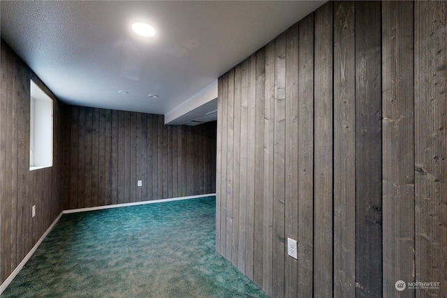 bonus room featuring wood walls and dark colored carpet