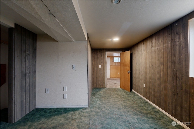 carpeted empty room featuring a textured ceiling and wood walls