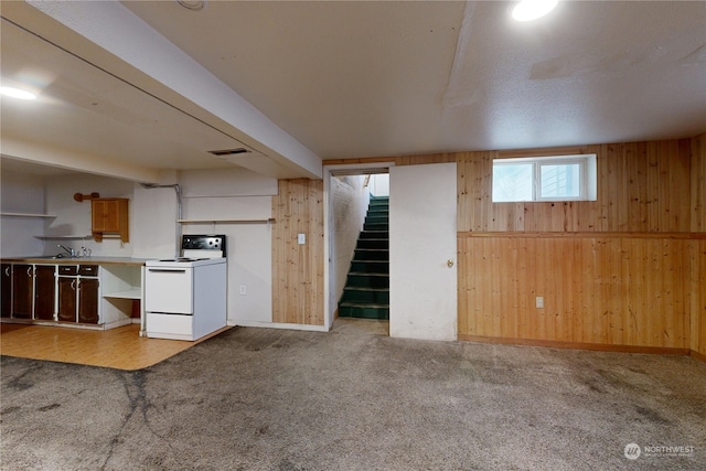 kitchen with sink, wooden walls, light carpet, and white range with electric stovetop