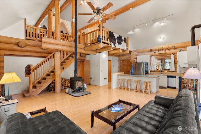 living room with track lighting, a wood stove, and light hardwood / wood-style flooring