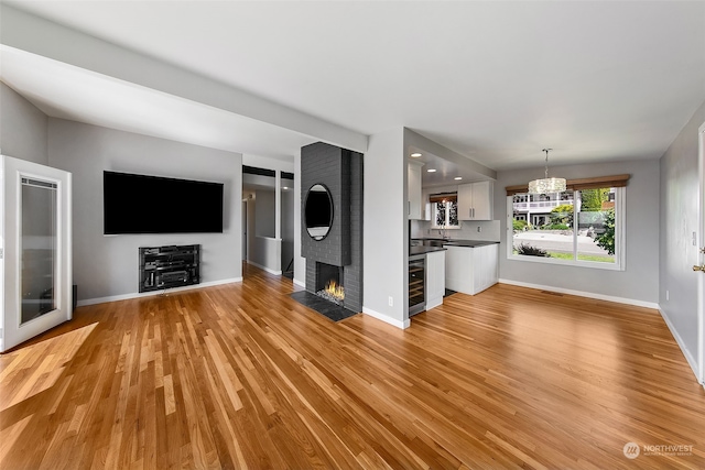 unfurnished living room featuring light hardwood / wood-style floors, a fireplace, and wine cooler