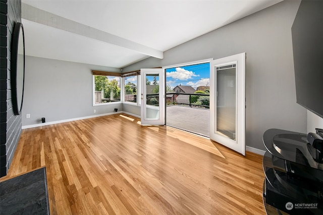 unfurnished living room featuring vaulted ceiling, light wood-type flooring, and french doors