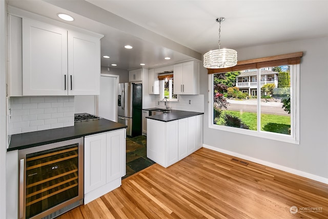 kitchen with pendant lighting, wine cooler, stainless steel fridge, and white cabinetry