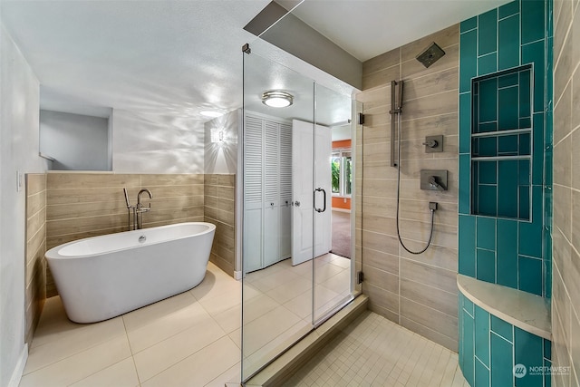 bathroom featuring tile floors, plus walk in shower, a textured ceiling, and tile walls