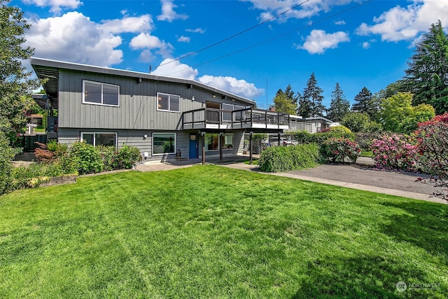 rear view of house with a lawn and a wooden deck