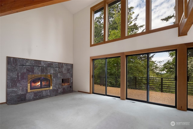 unfurnished living room featuring high vaulted ceiling, carpet flooring, and a high end fireplace