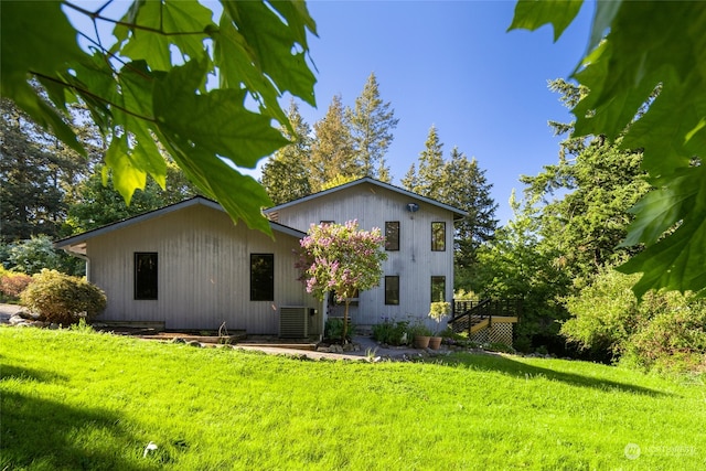 rear view of property featuring central AC and a lawn