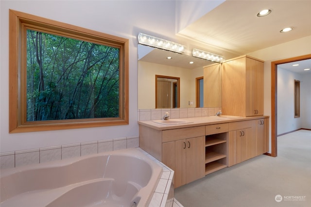 bathroom featuring oversized vanity, double sink, and tiled tub