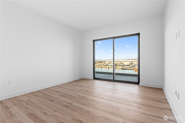 unfurnished room featuring a water view and light hardwood / wood-style flooring