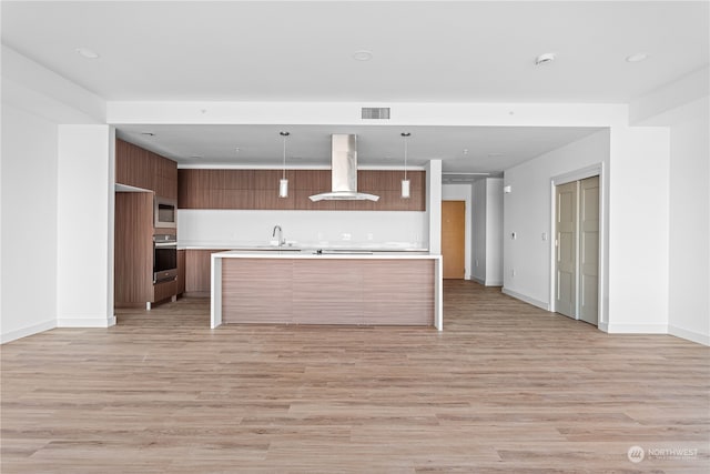 kitchen with light hardwood / wood-style flooring, ventilation hood, a kitchen island with sink, decorative light fixtures, and stainless steel appliances