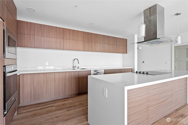 kitchen with light hardwood / wood-style flooring, sink, pendant lighting, appliances with stainless steel finishes, and island exhaust hood