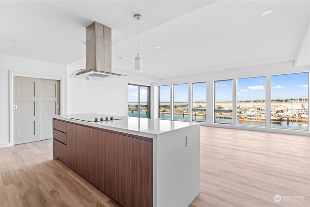 kitchen with hanging light fixtures, a center island, light hardwood / wood-style floors, island range hood, and electric cooktop