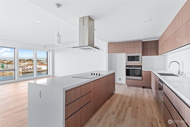 kitchen featuring sink, stainless steel appliances, light hardwood / wood-style flooring, pendant lighting, and island range hood