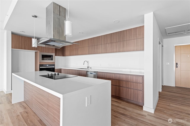 kitchen with sink, black appliances, decorative light fixtures, island exhaust hood, and light wood-type flooring