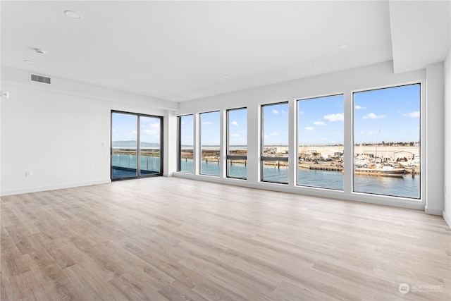 spare room featuring a water view and light wood-type flooring